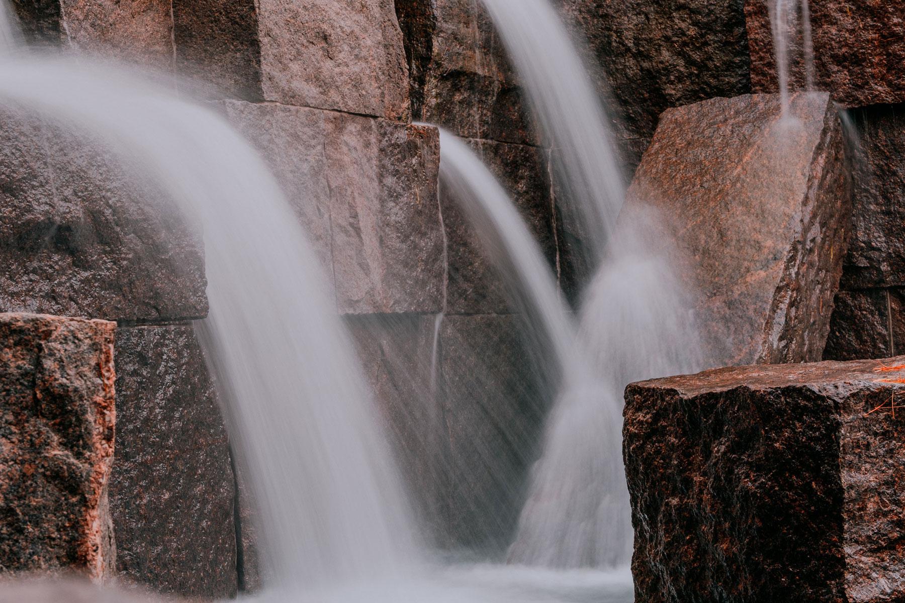 Cascading waterfalls framed by large stone blocks and lush greenery at the Franklin Delano Roosevelt Memorial.