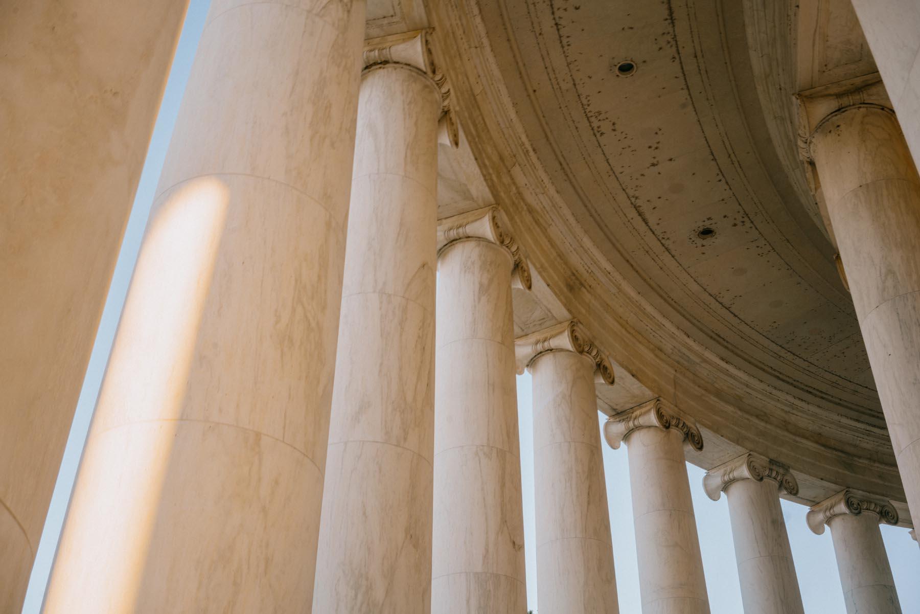 Interior view of the Thomas Jefferson Memorial showcasing the tall marble columns and curved ceiling with sunlight streaming through.