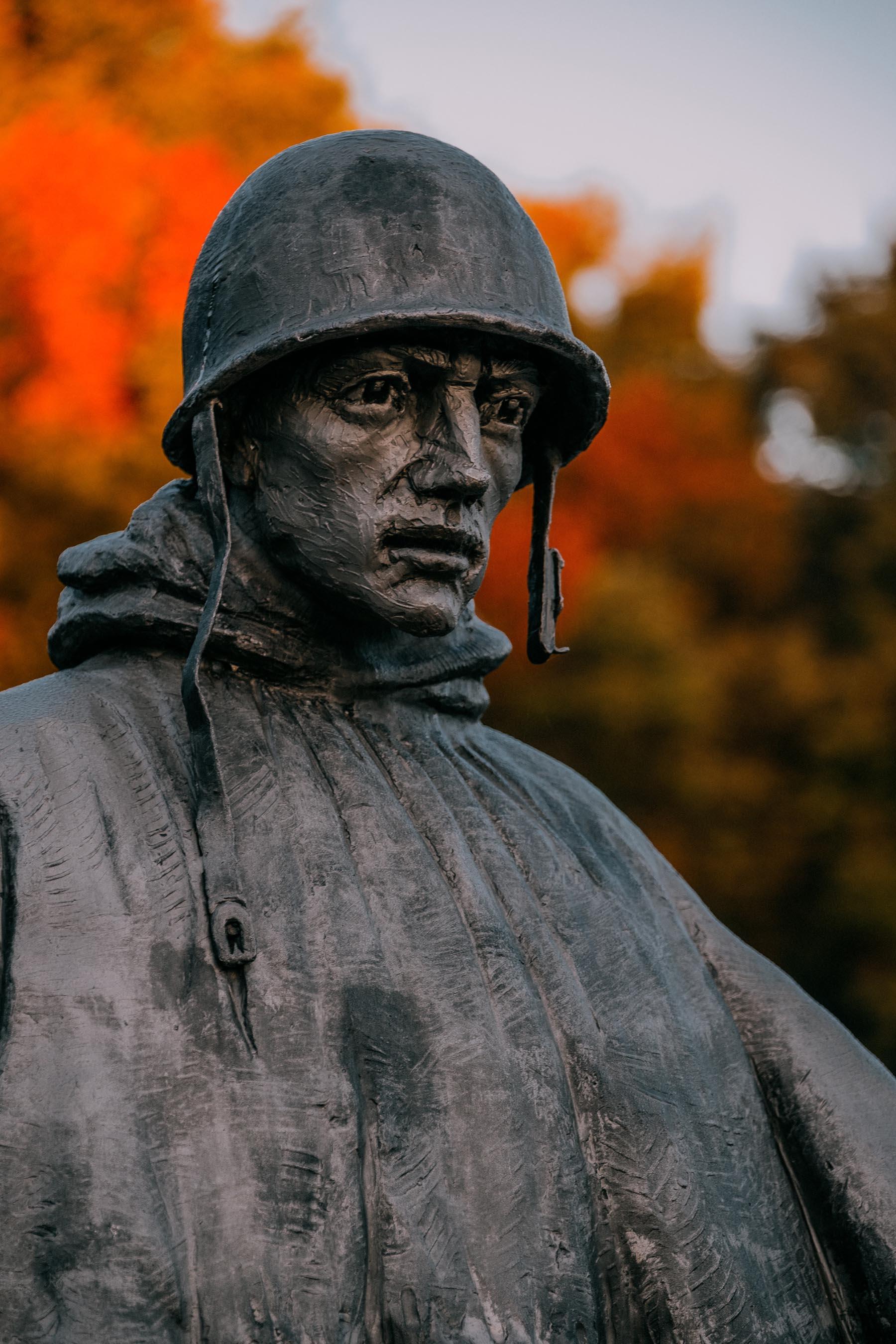 A single soldier statue at the Korean War Veterans Memorial, silhouetted against a soft evening sky.