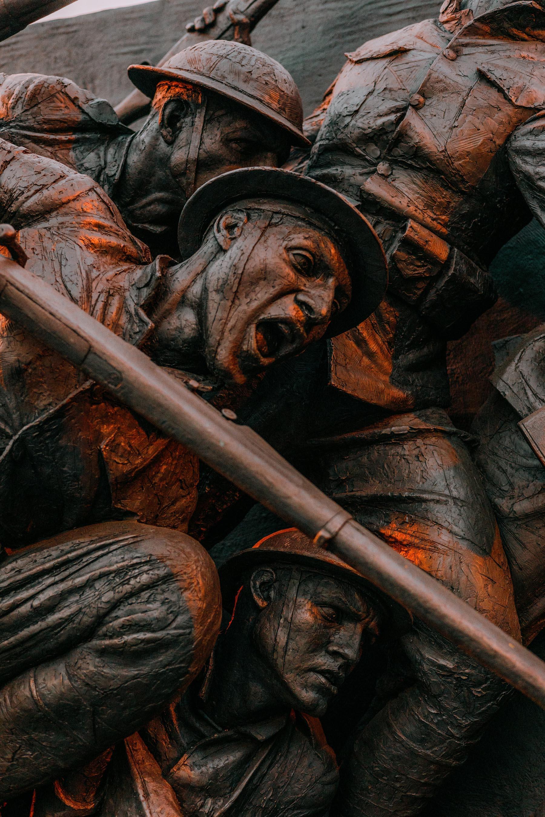 Detailed view of bronze soldiers from the WWI memorial in Washington DC, highlighting intense expressions and dramatic poses symbolizing their bravery and struggle.