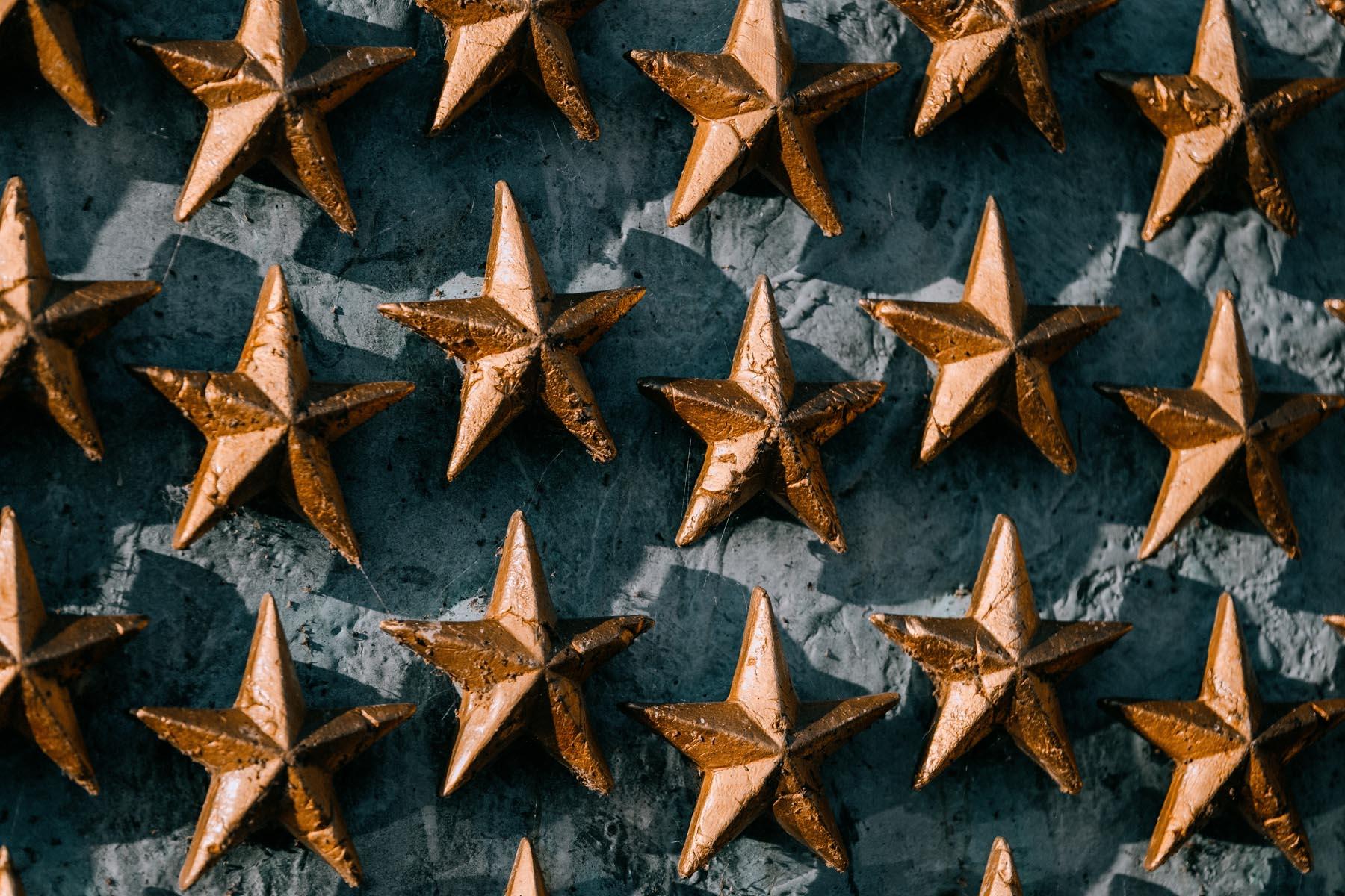 Close-up of individual gold stars from the Wall of Stars at the WWII Memorial, highlighting their textured metallic surface.